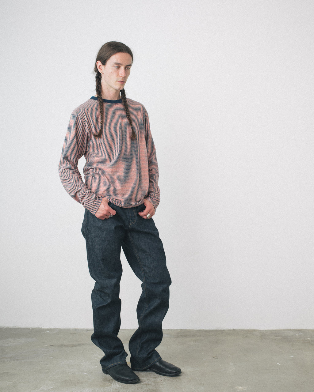 Person wearing a striped tee and dark jeans against a plain white background